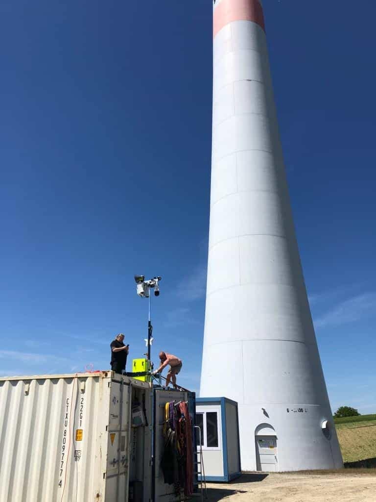 Mini-Turm auf Container vor einem großem Windrad Mini-Turm auf Container vor einem großem Windrad
